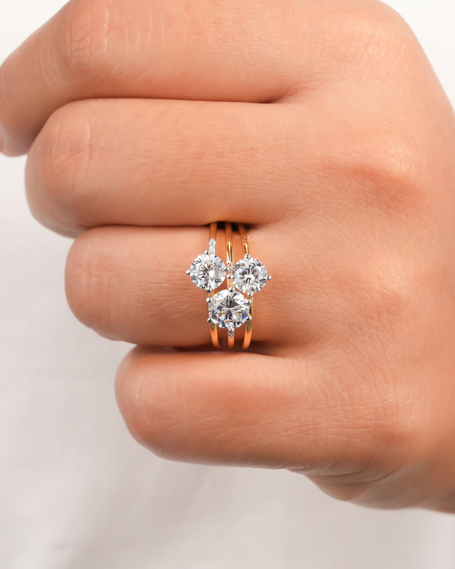 Hand wearing a round three stone lab grown diamond cluster ring with a split gold band, front view