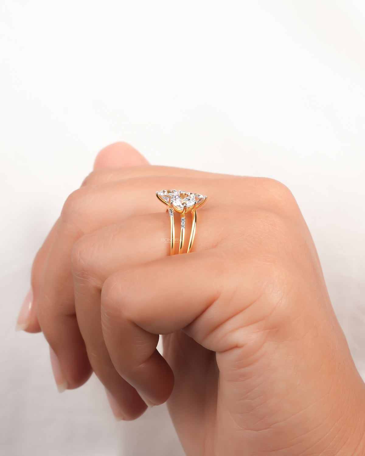 Side view of a round three stone lab grown diamond cluster ring in yellow gold worn on a hand, split band visible