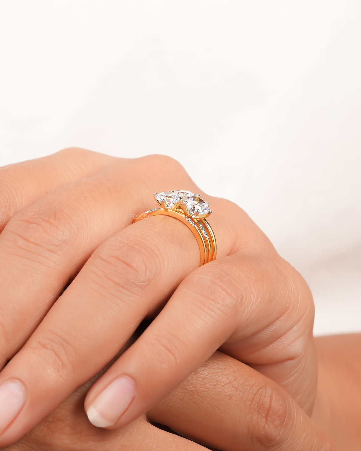 Close side view of a round three stone lab grown diamond cluster ring in yellow gold worn on a finger