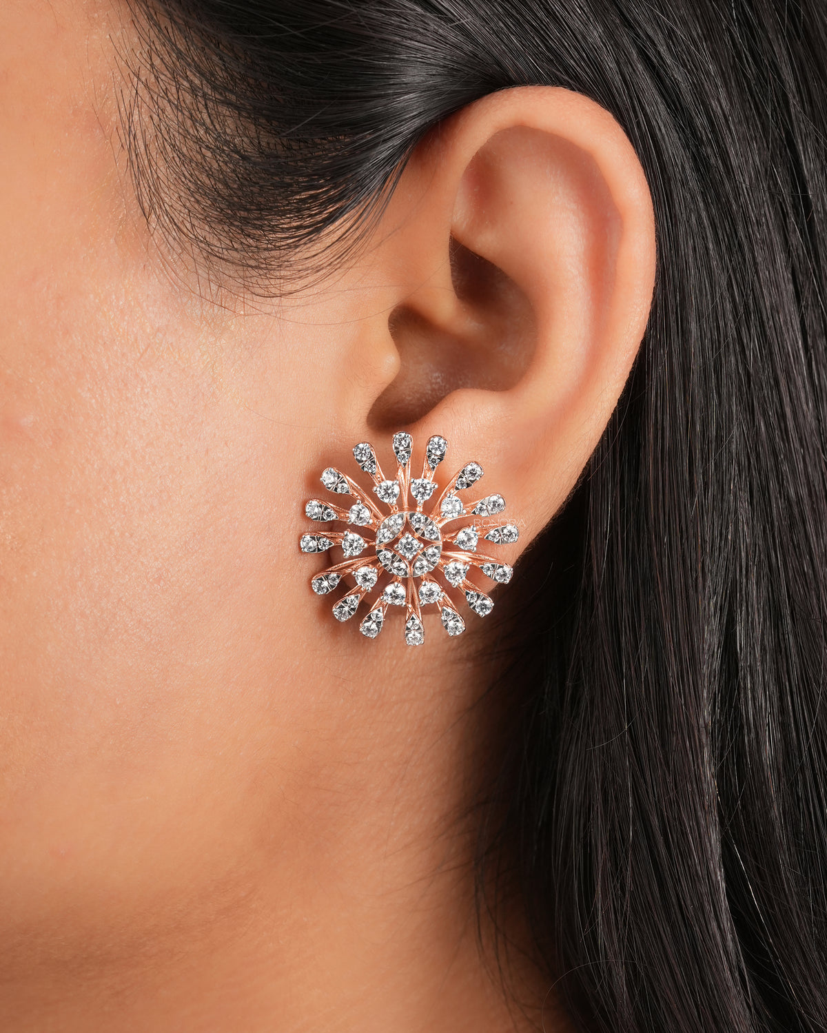 Starburst cluster lab grown diamond earring in rose gold worn on a woman's ear, close-up
