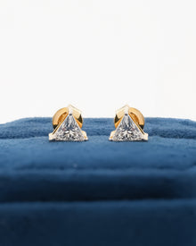 Pair of trillion cut lab grown diamond earrings in yellow gold standing on a blue velvet box