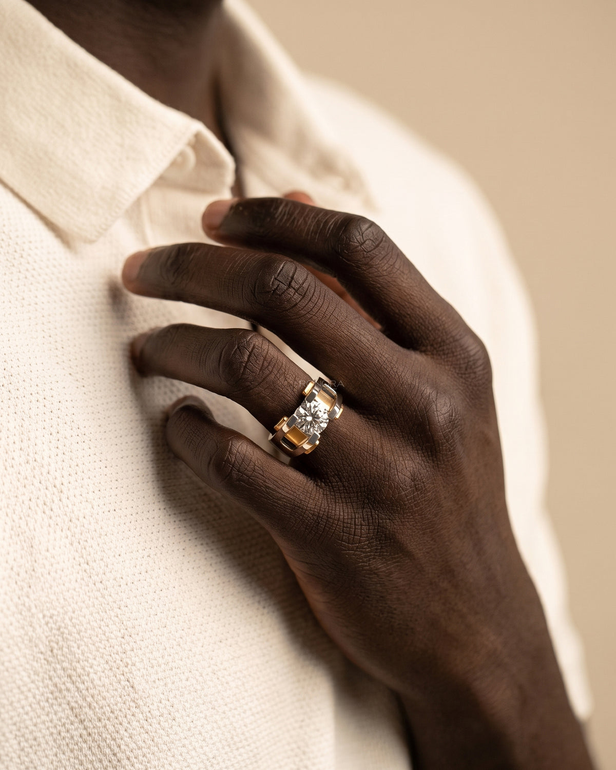 Hand wearing a round lab grown diamond solitaire engagement ring in two tone white and yellow gold, model in cream shirt