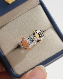 Top view of a round lab grown diamond solitaire engagement ring with two tone gold band in a navy and cream ring box