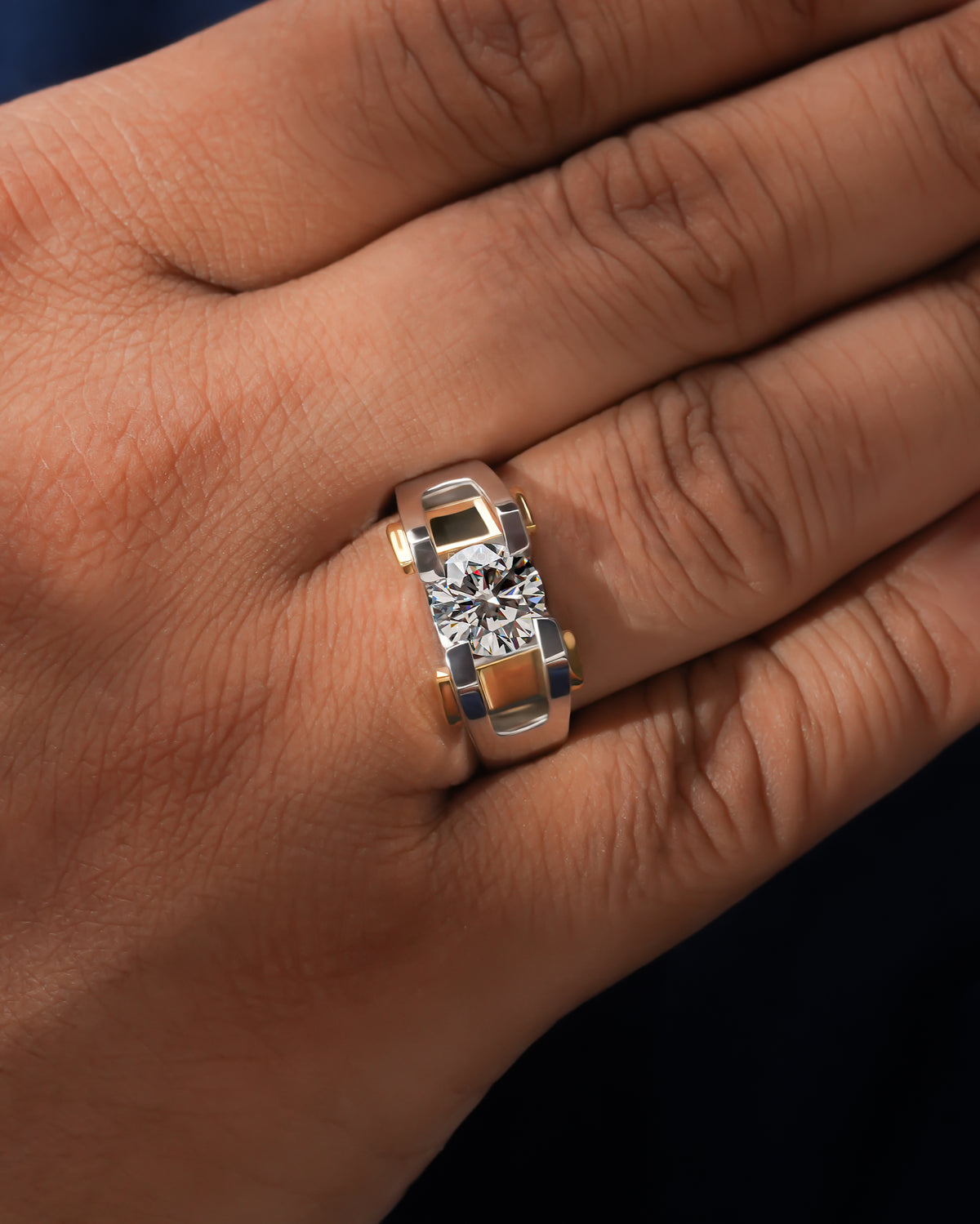 Round lab grown diamond solitaire engagement ring in two tone gold worn on a hand, close-up on the finger