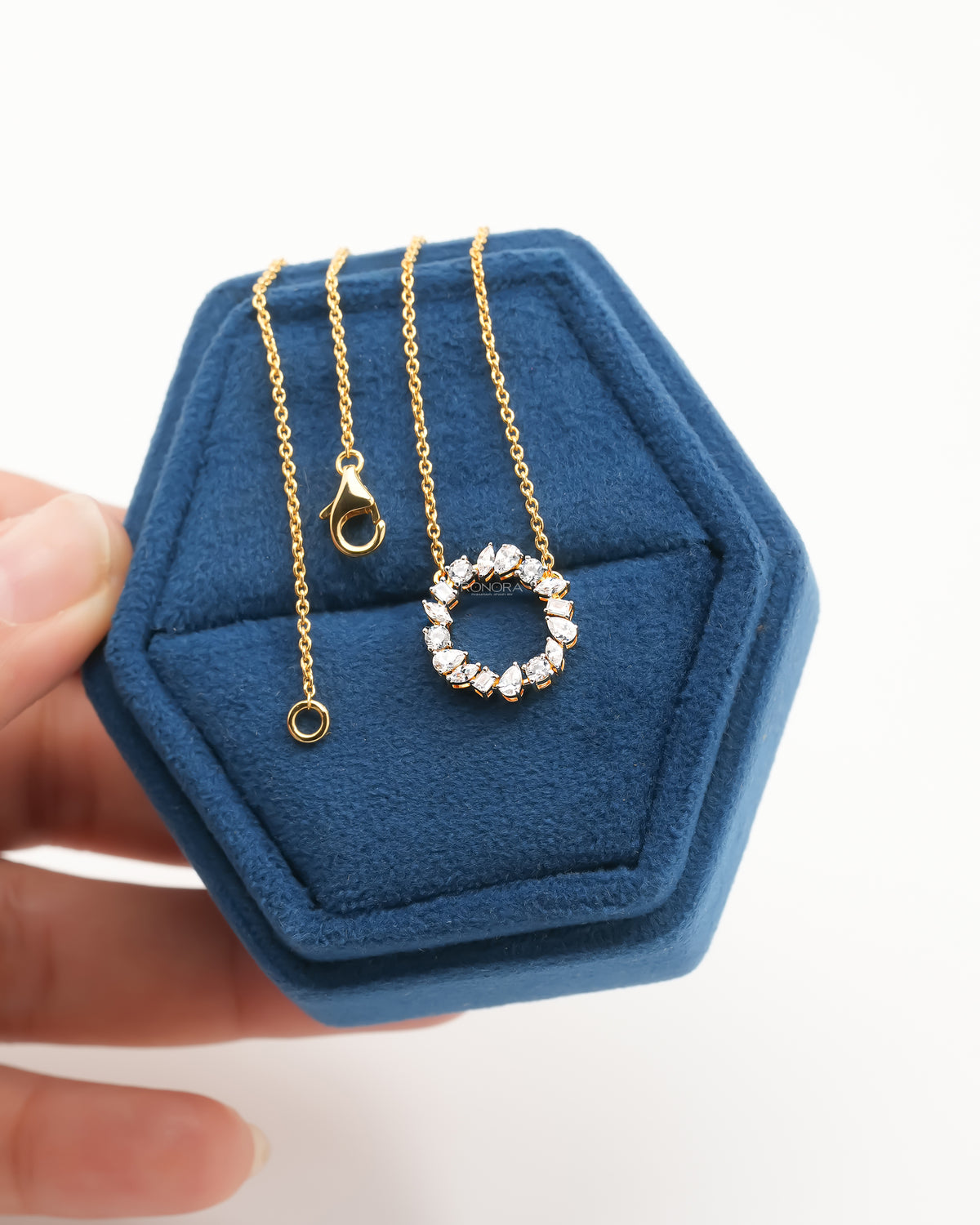 Wreath lab grown diamond necklace in yellow gold laid on a blue velvet ring box, open circle pendant facing front