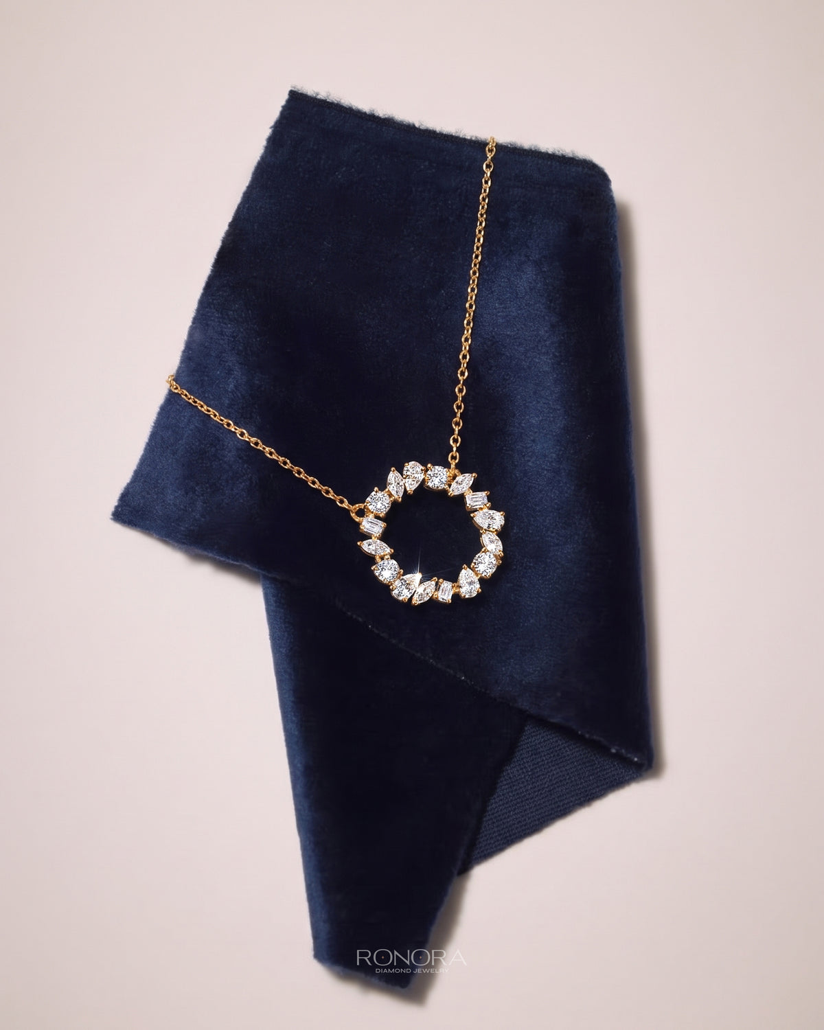 Wreath lab grown diamond necklace in yellow gold on a navy velvet pouch, open circle pendant of mixed shape stones