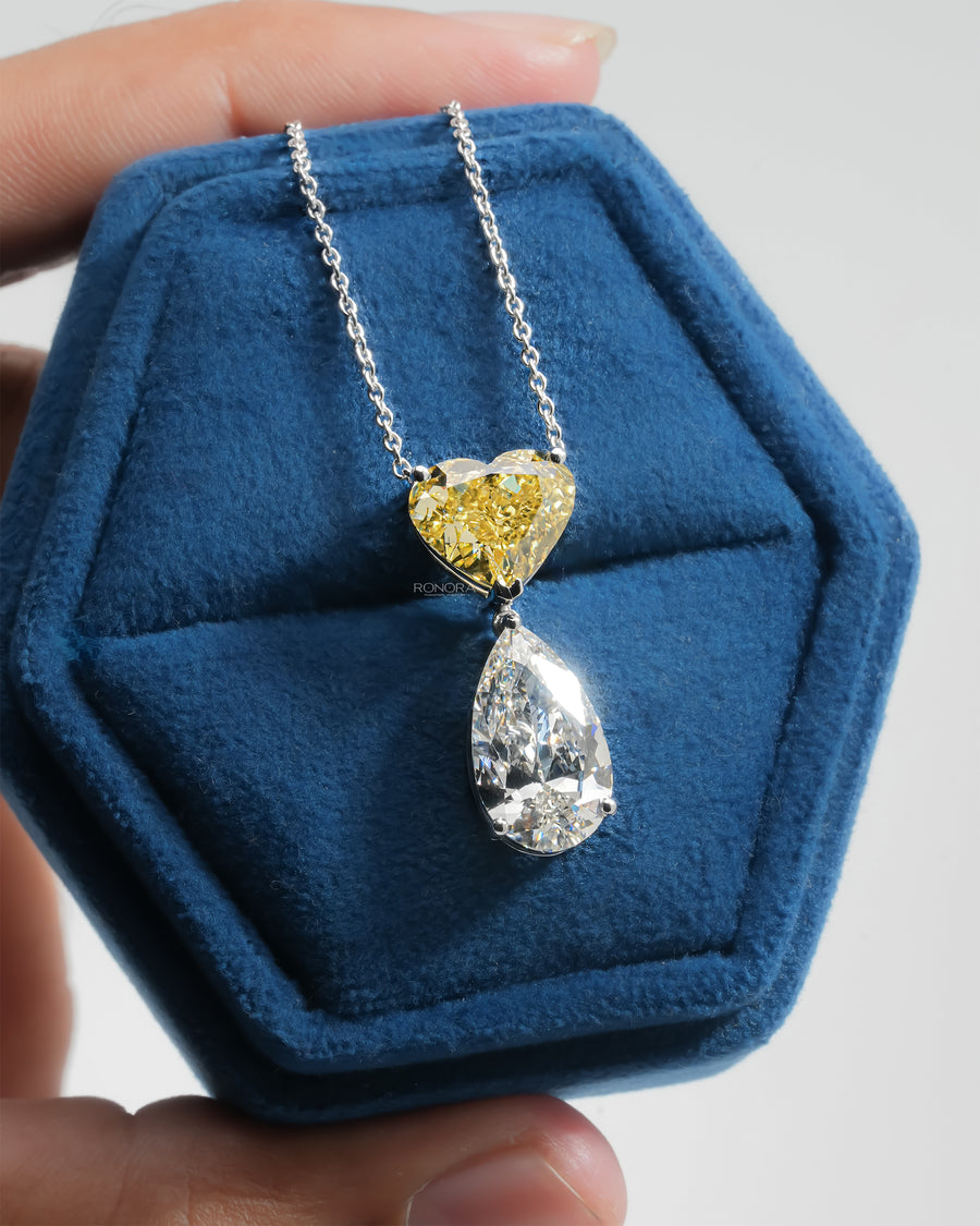 Yellow heart and white pear lab grown diamond necklace on a white gold chain, shown in a blue velvet jewelry box