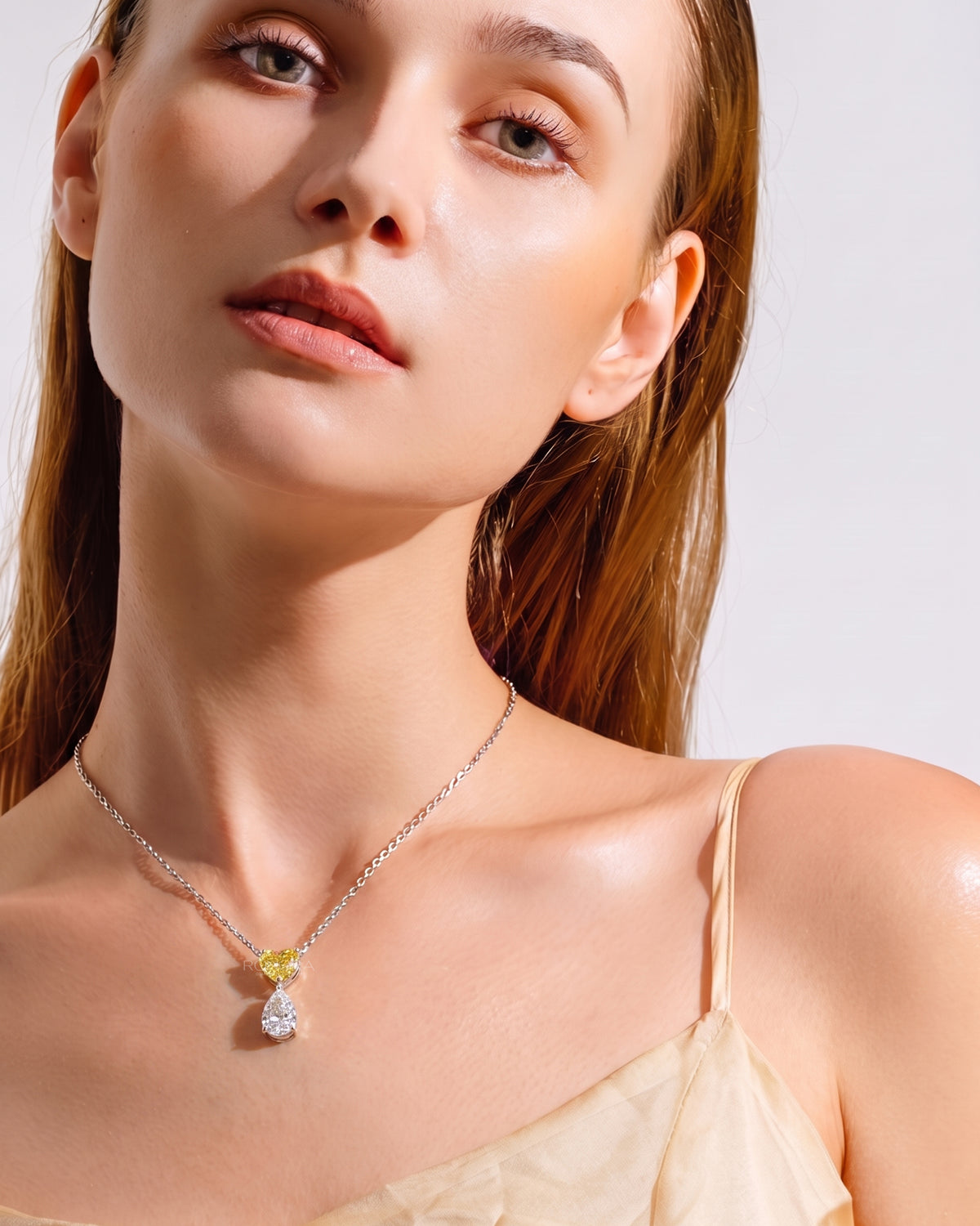 Model wearing a yellow heart lab grown diamond necklace with a white pear drop on a fine white gold chain