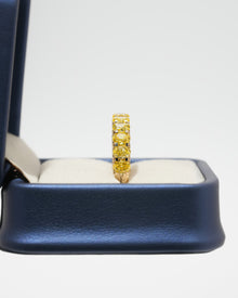 Side view of a yellow lab grown diamond oval eternity band standing upright in a navy blue ring box