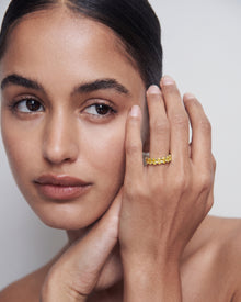 Model touching her face and wearing a yellow lab grown diamond oval eternity band in yellow gold on her ring finger