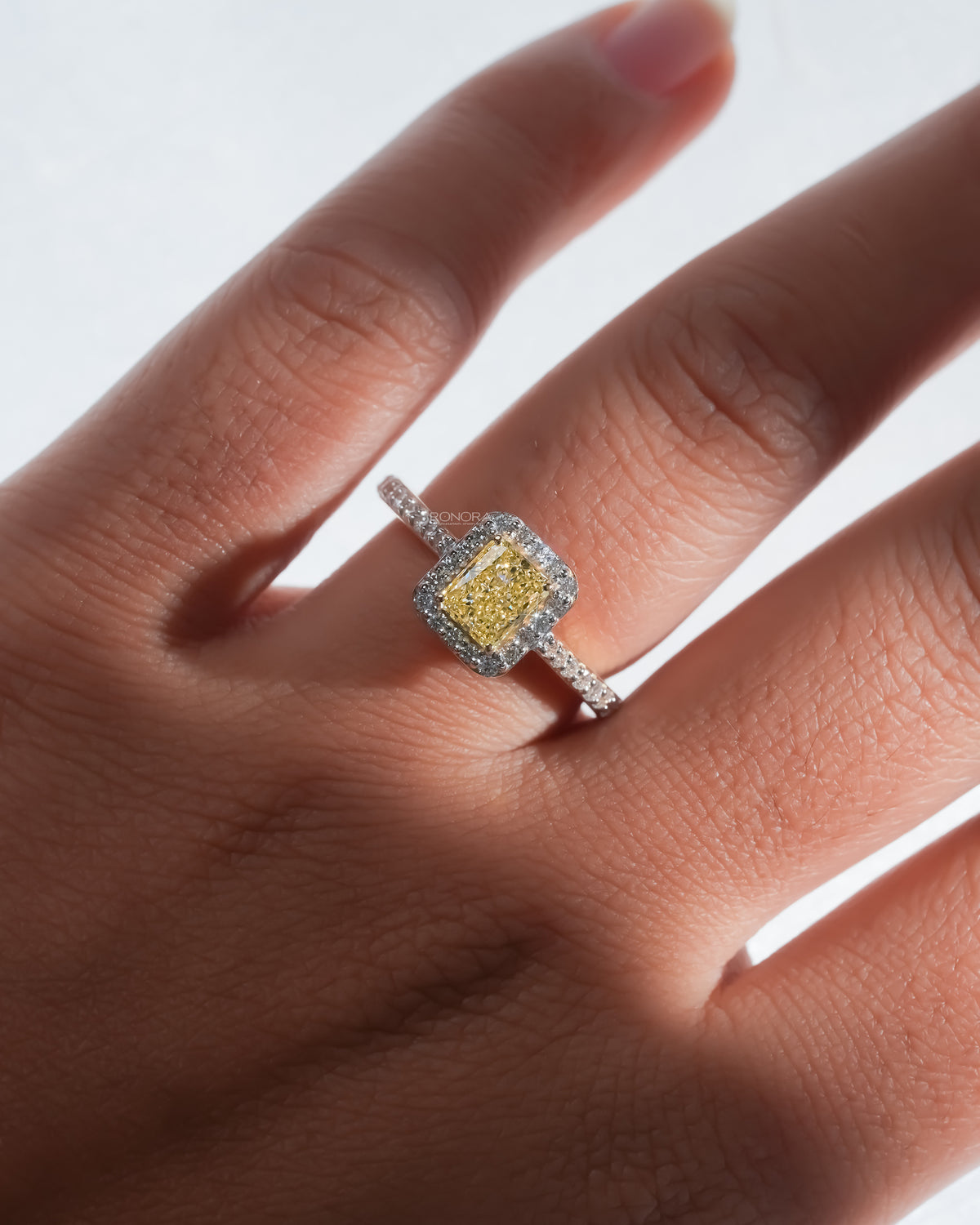 Fancy yellow lab grown diamond halo ring worn on the hand from above