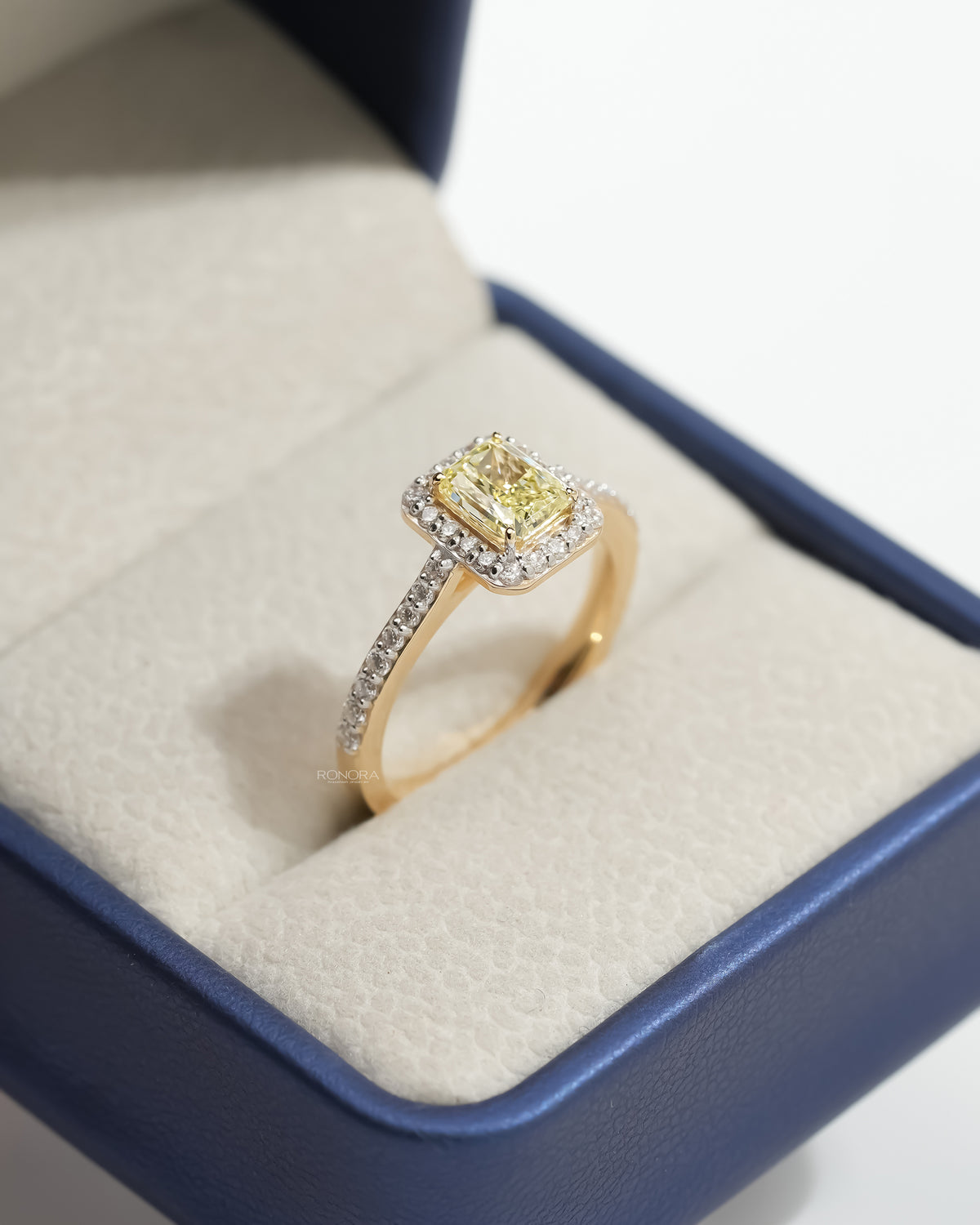 Fancy yellow lab grown diamond halo ring angled in a Ronora box