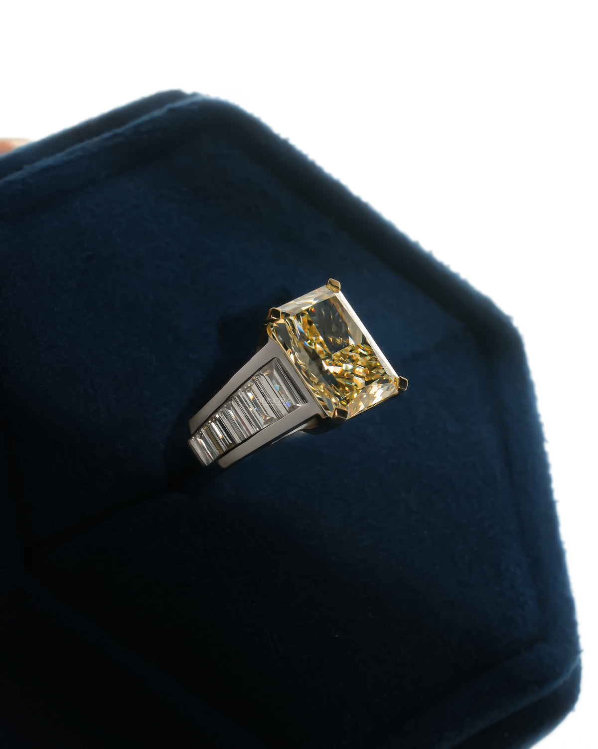 Fancy yellow radiant lab grown diamond ring resting on blue velvet