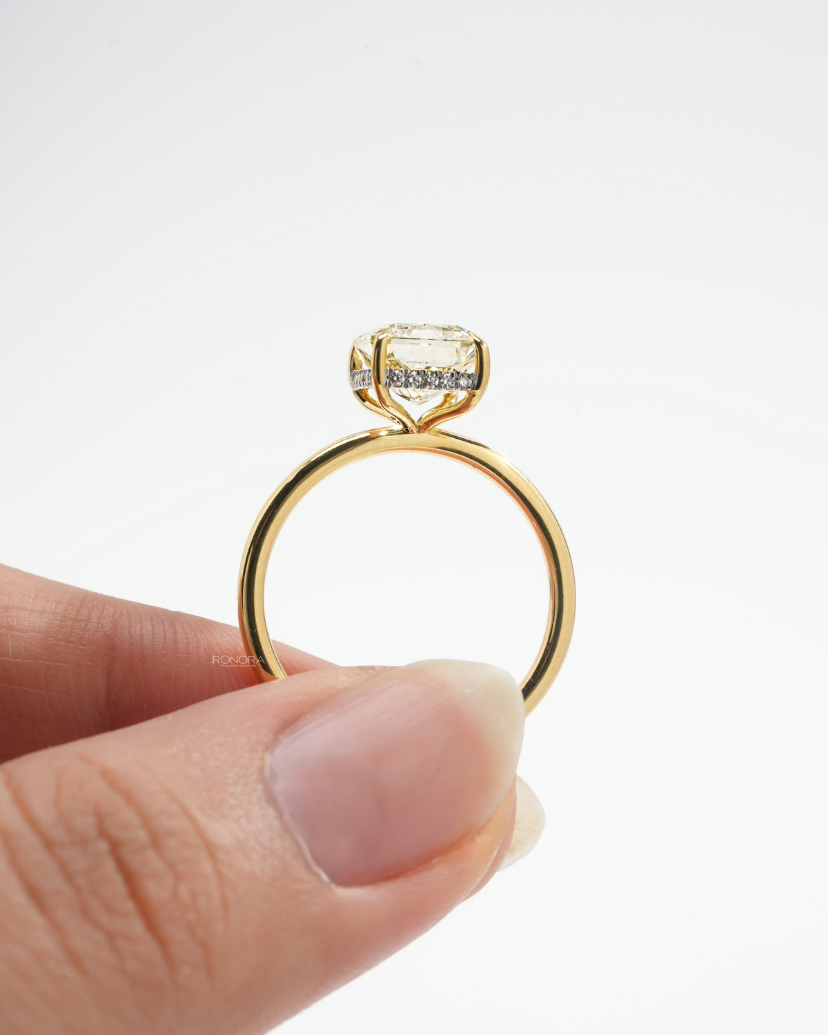 Side profile of a yellow radiant lab grown diamond solitaire ring with a hidden halo under the stone, yellow gold band